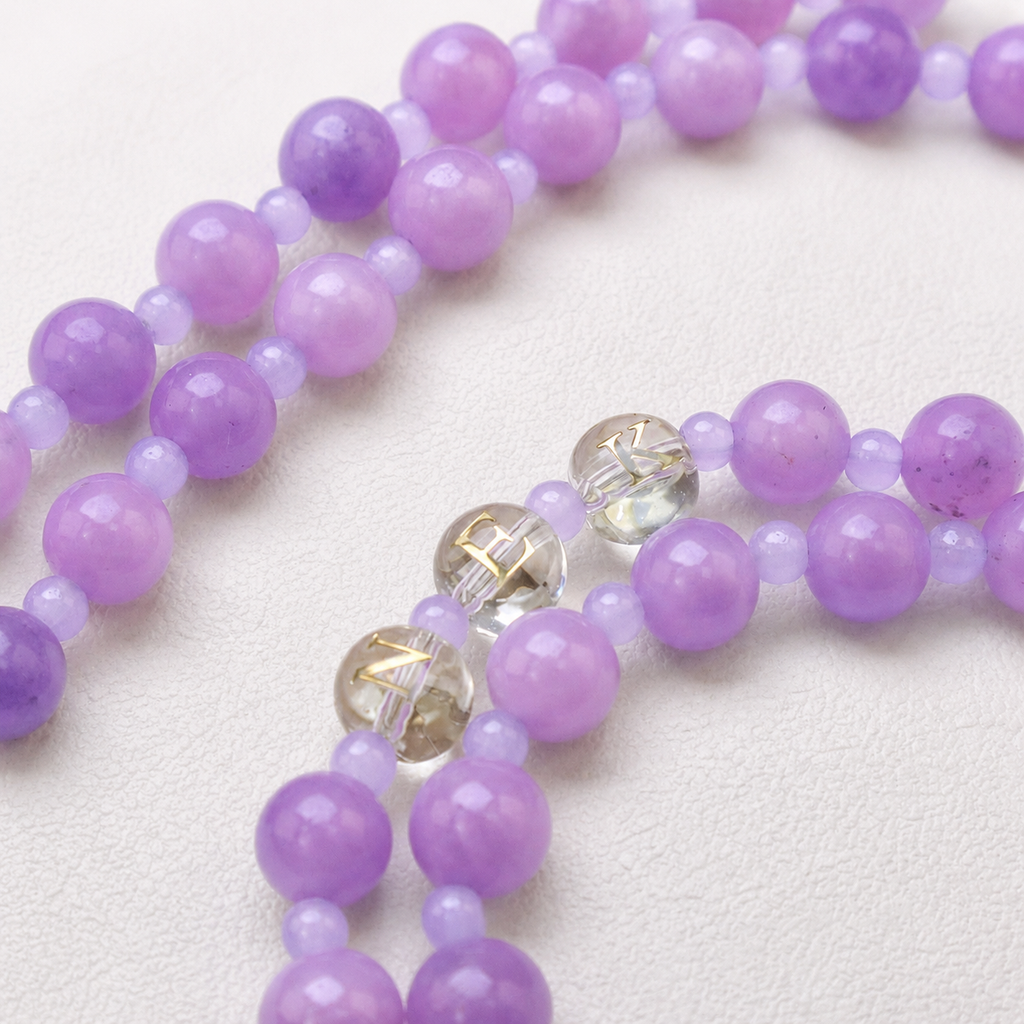 Close-up of a handmade rosary with lavender beads, colorful floral glass beads, and elegant handcrafted details.