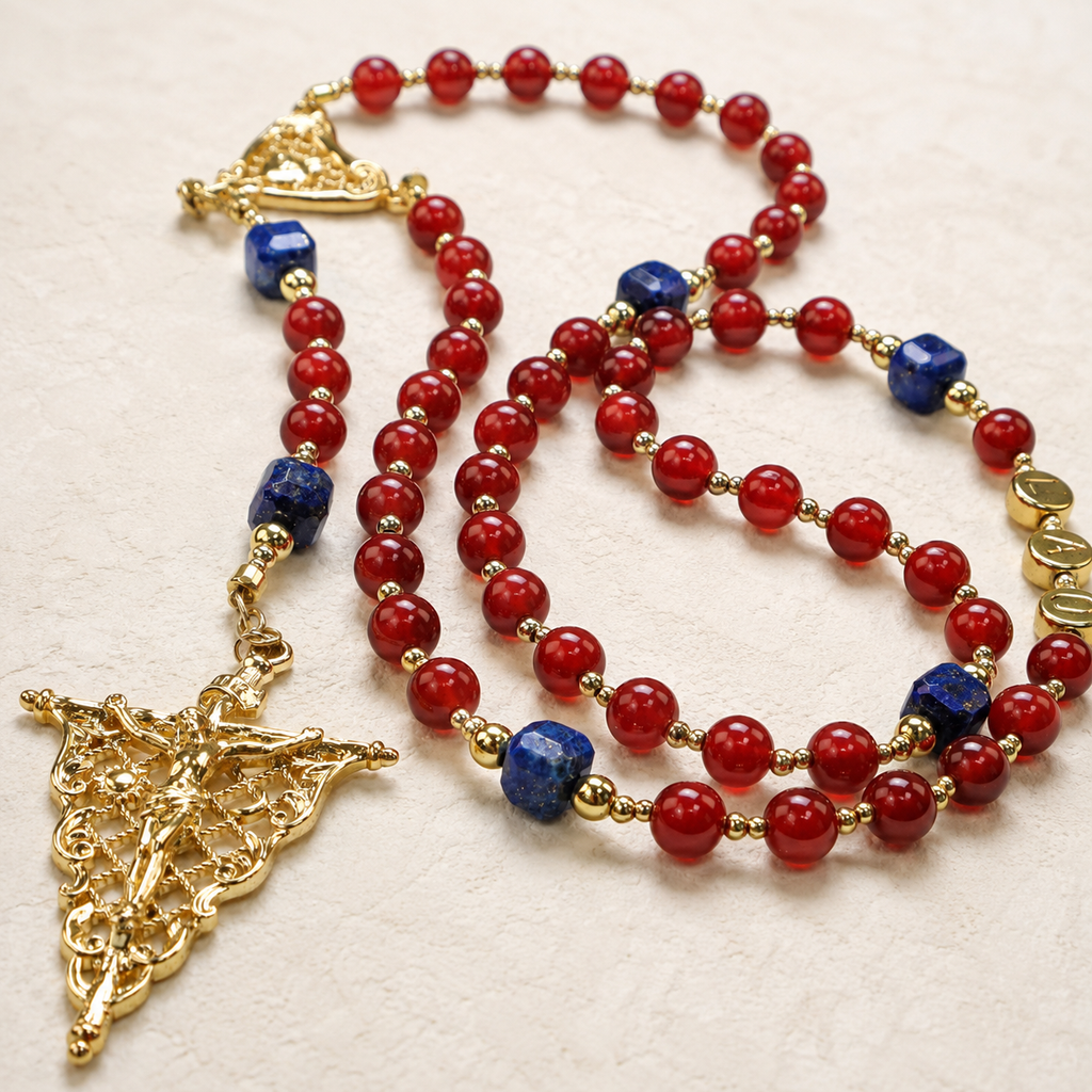 Close-up of a gold crucifix pendant on a red Catholic rosary featuring intricate religious details and handcrafted design.