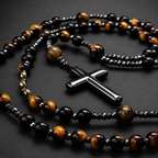 Close-up of handmade men's Catholic rosary featuring black stone beads, metallic accents, and detailed crucifix craftsmanship.