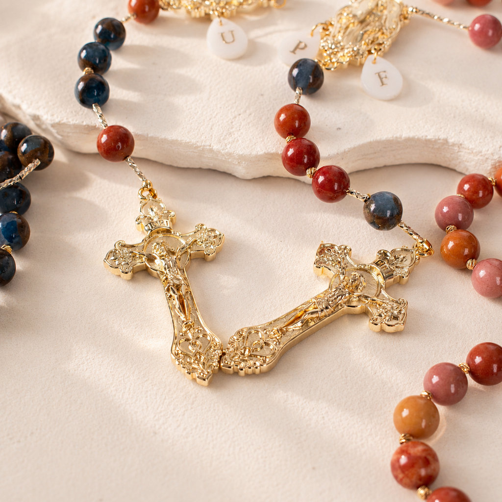 Close-up of handmade Catholic wedding rosaries with gemstone-style beads, Marian medals, letter charms, and gold-tone crucifixes.