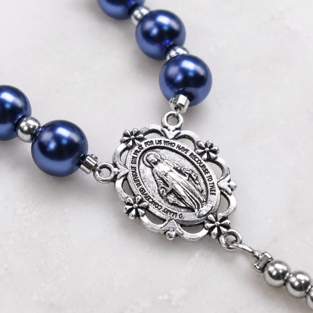 Close-up of deep blue pearl rosary beads with silver Our Lady medal, St. Benedict style details, and handcrafted Catholic prayer design.