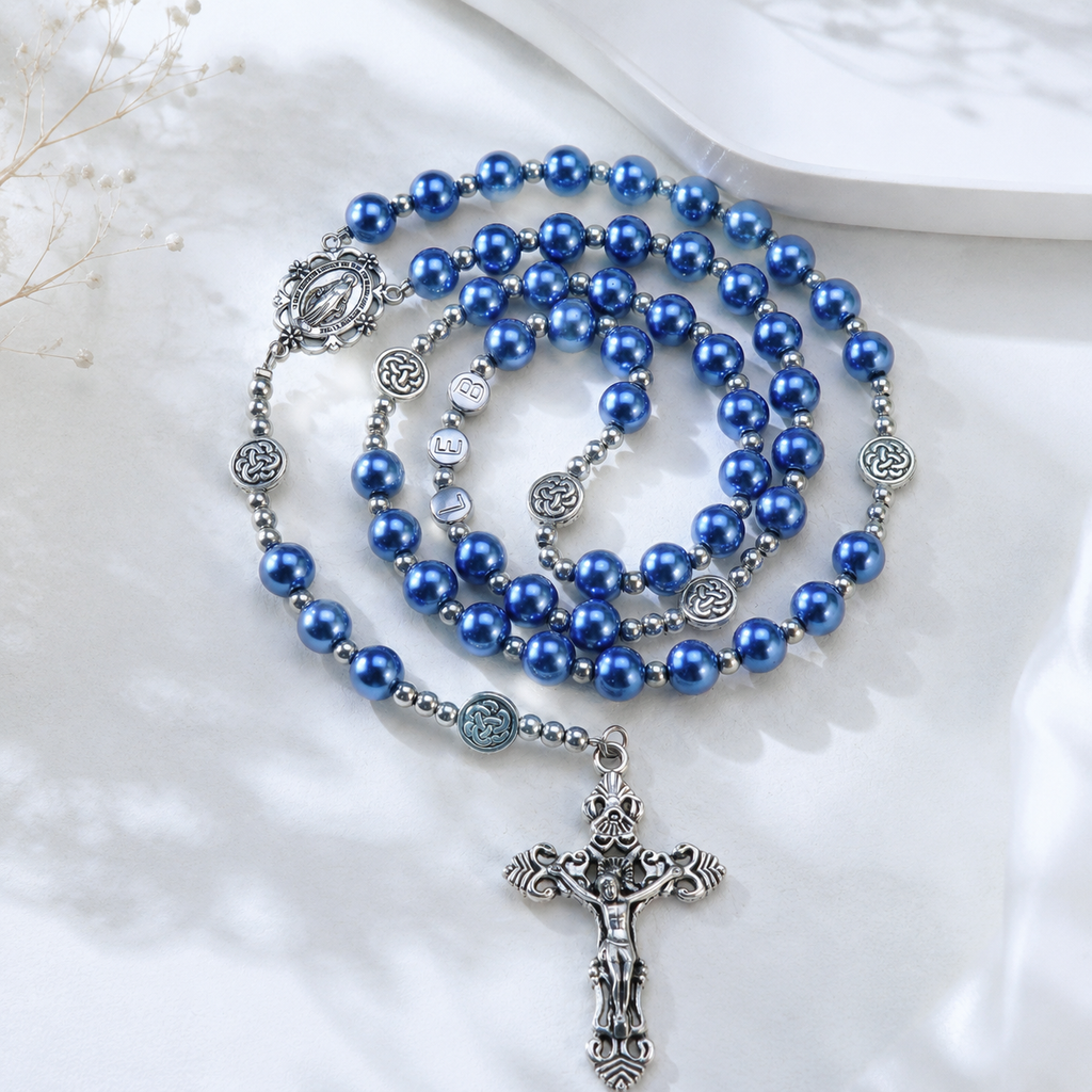 Handmade Catholic rosary featuring glossy blue pearl beads, silver centerpiece medal, and detailed crucifix pendant for personal devotion.