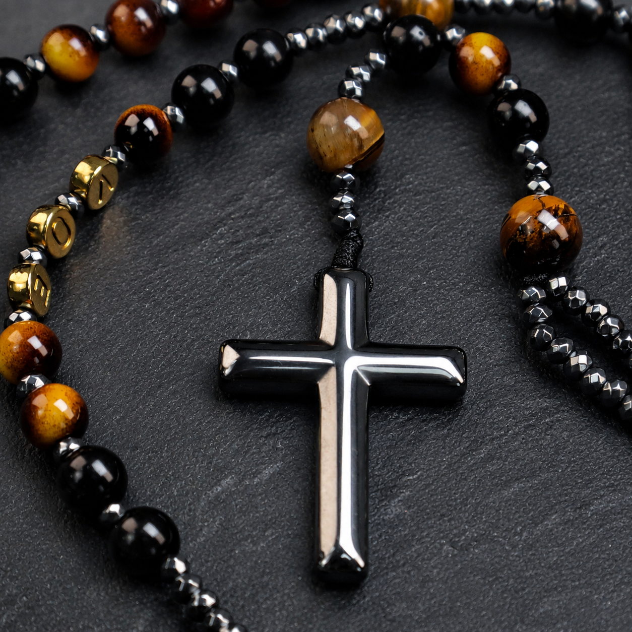 Detailed silver cross pendant attached to a men's black rosary with natural stone beads and classic Catholic design.