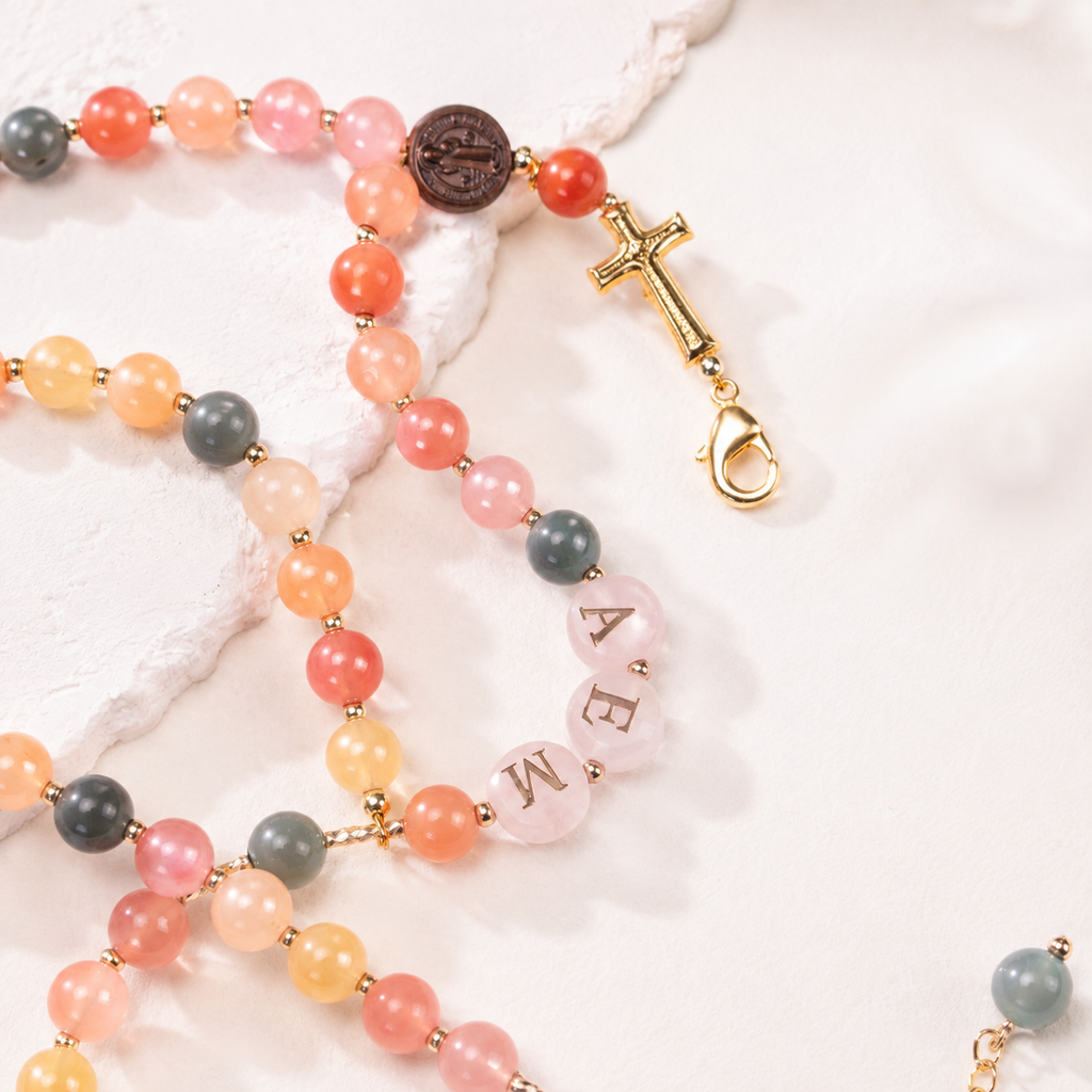 Personalized Catholic rosary bracelet featuring custom name letter beads, pastel gemstone-style beads, and gold-tone accents.