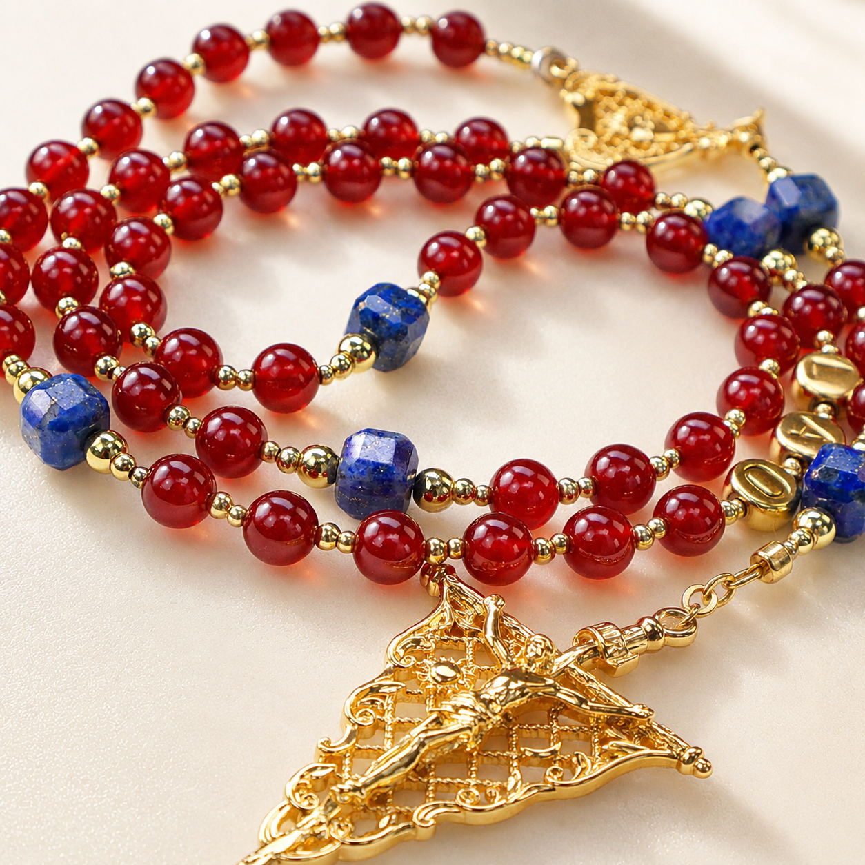 Handmade red Catholic rosary with deep red beads, blue stone accents, gold-tone details, and an ornate crucifix pendant for prayer and devotion.