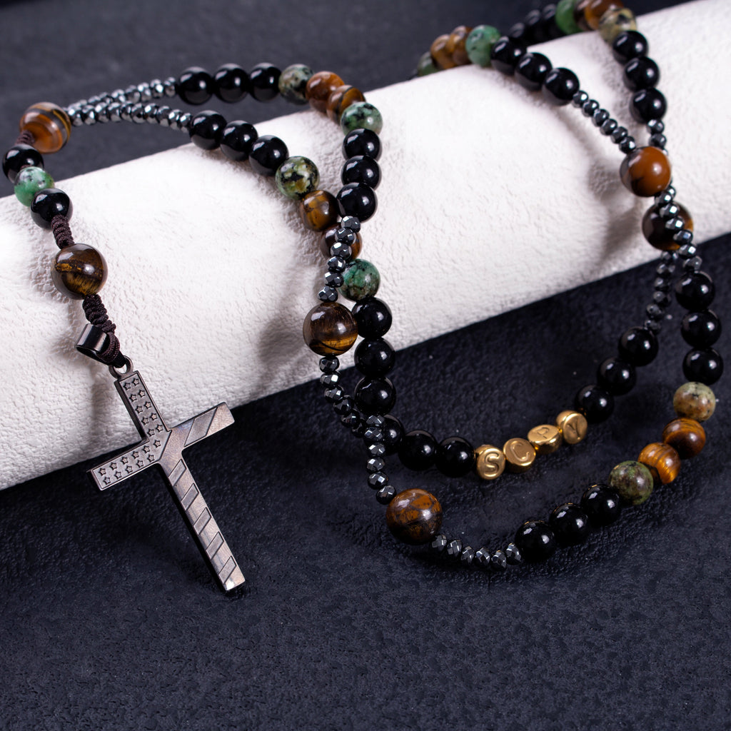 Men’s Catholic prayer beads with matte black beads, tiger-eye style beads, green stone accents, and dark metallic spacers.