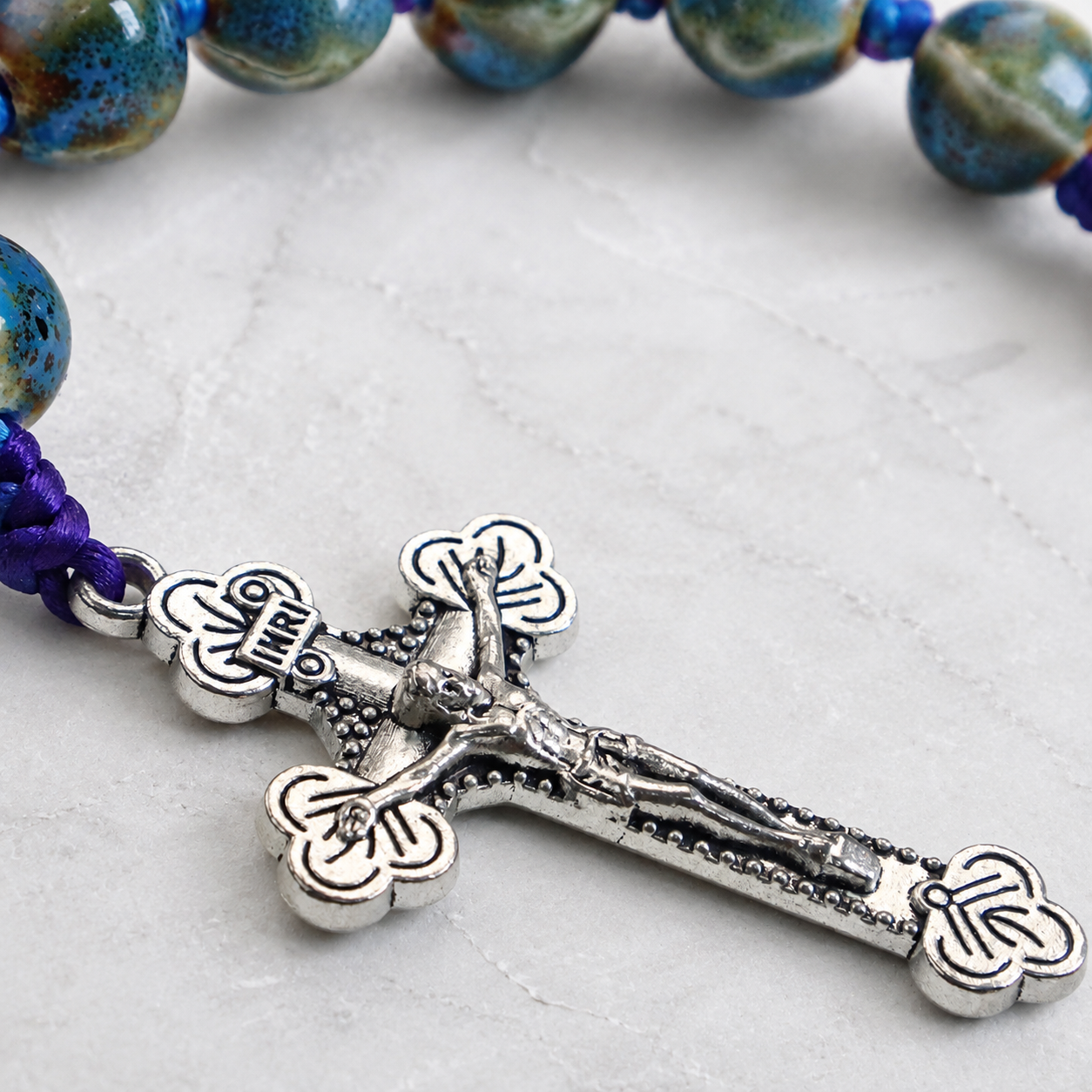 Silver crucifix pendant on handmade Catholic prayer beads with colorful cord and ceramic-style beads for daily devotion.