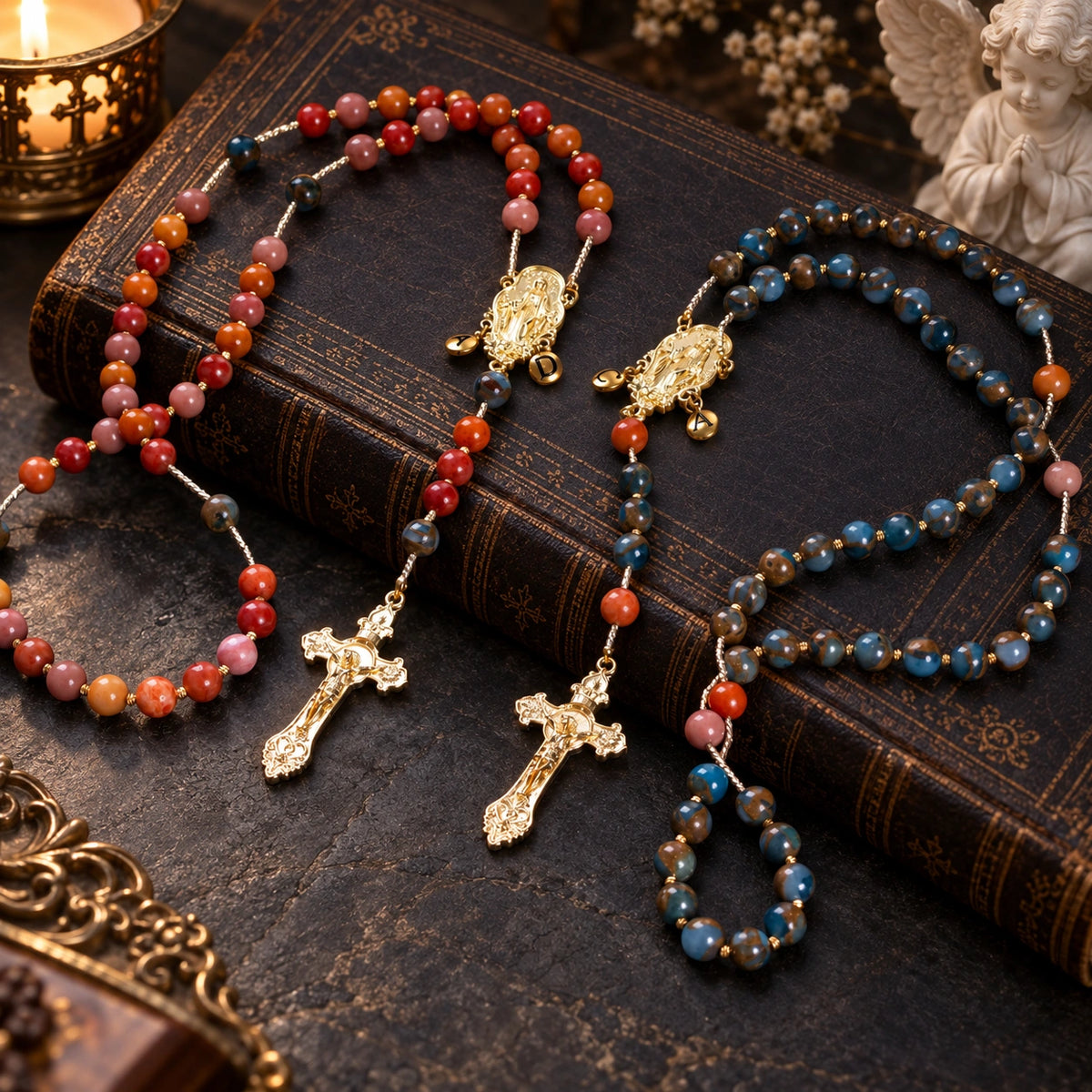 Matching Catholic wedding rosary set for bride and groom with warm red, pink, and blue-brown beads and gold religious details.