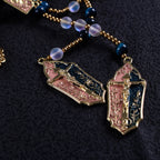 Close-up of Catholic wedding rosaries with gold crucifix pendants, Marian medals, and coordinated blue and luminous bead details.