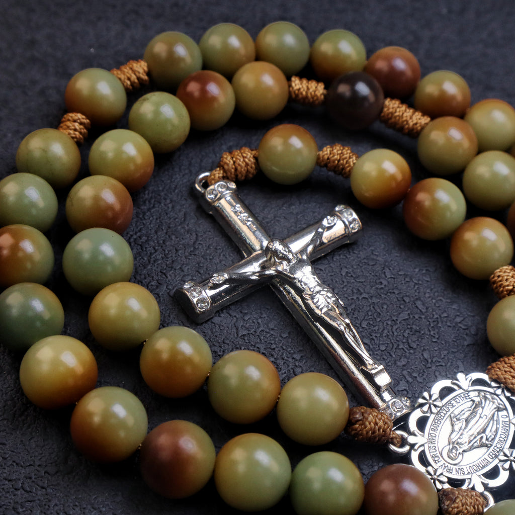 Detailed silver crucifix pendant on a men's rosary with natural earth tone beads and rustic Catholic craftsmanship.