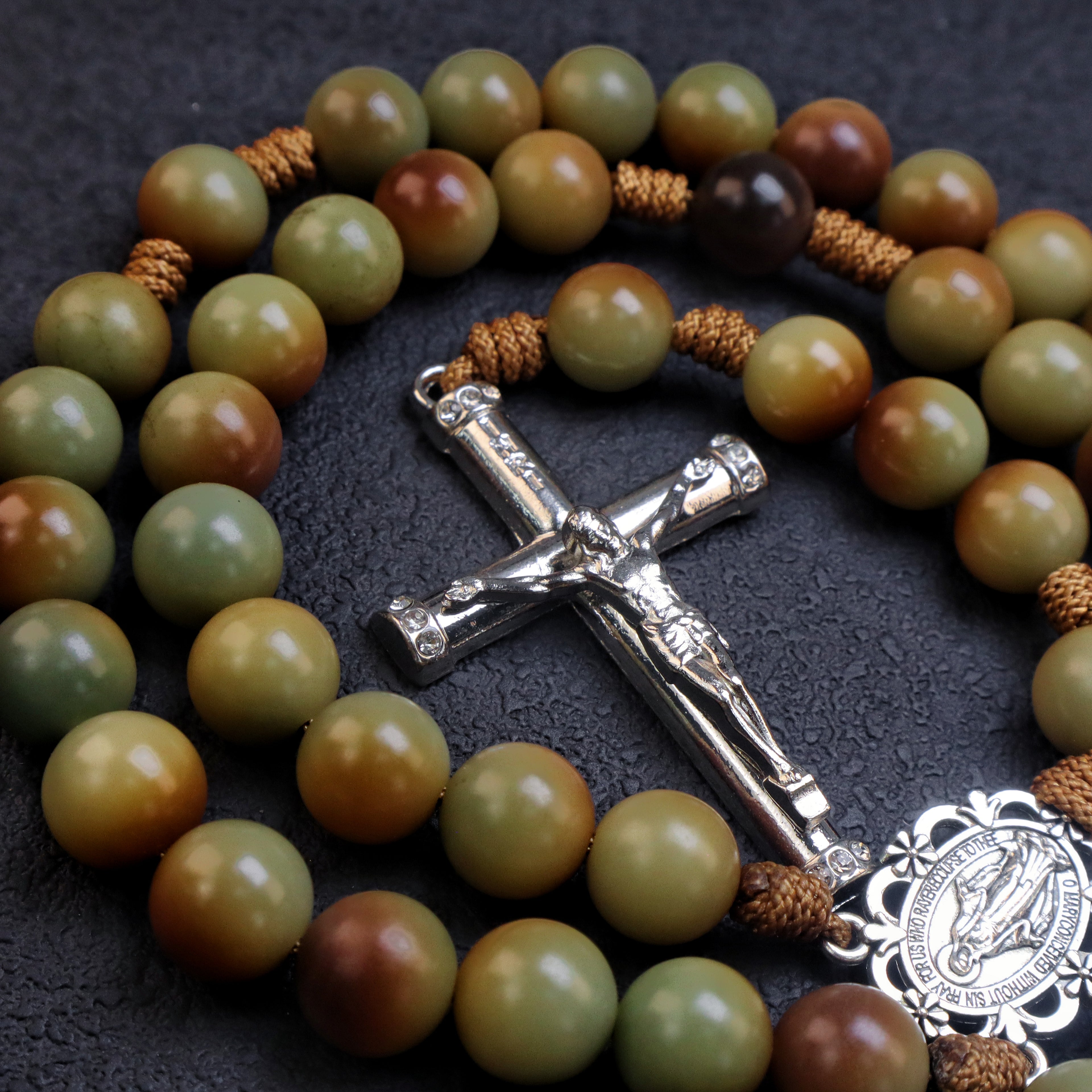 Detailed silver crucifix pendant on a men's rosary with natural earth tone beads and rustic Catholic craftsmanship.