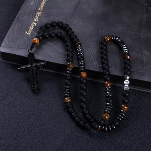 Close-up of a black crucifix pendant on a handmade men’s Catholic rosary with matte black prayer beads.