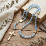 Handcrafted blue glass Catholic rosary with gold cross on a wooden background, ideal religious gift for Baptism.