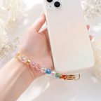 Rainbow crystal Christian phone charm attached to a phone, adding a colorful and meaningful faith accessory
