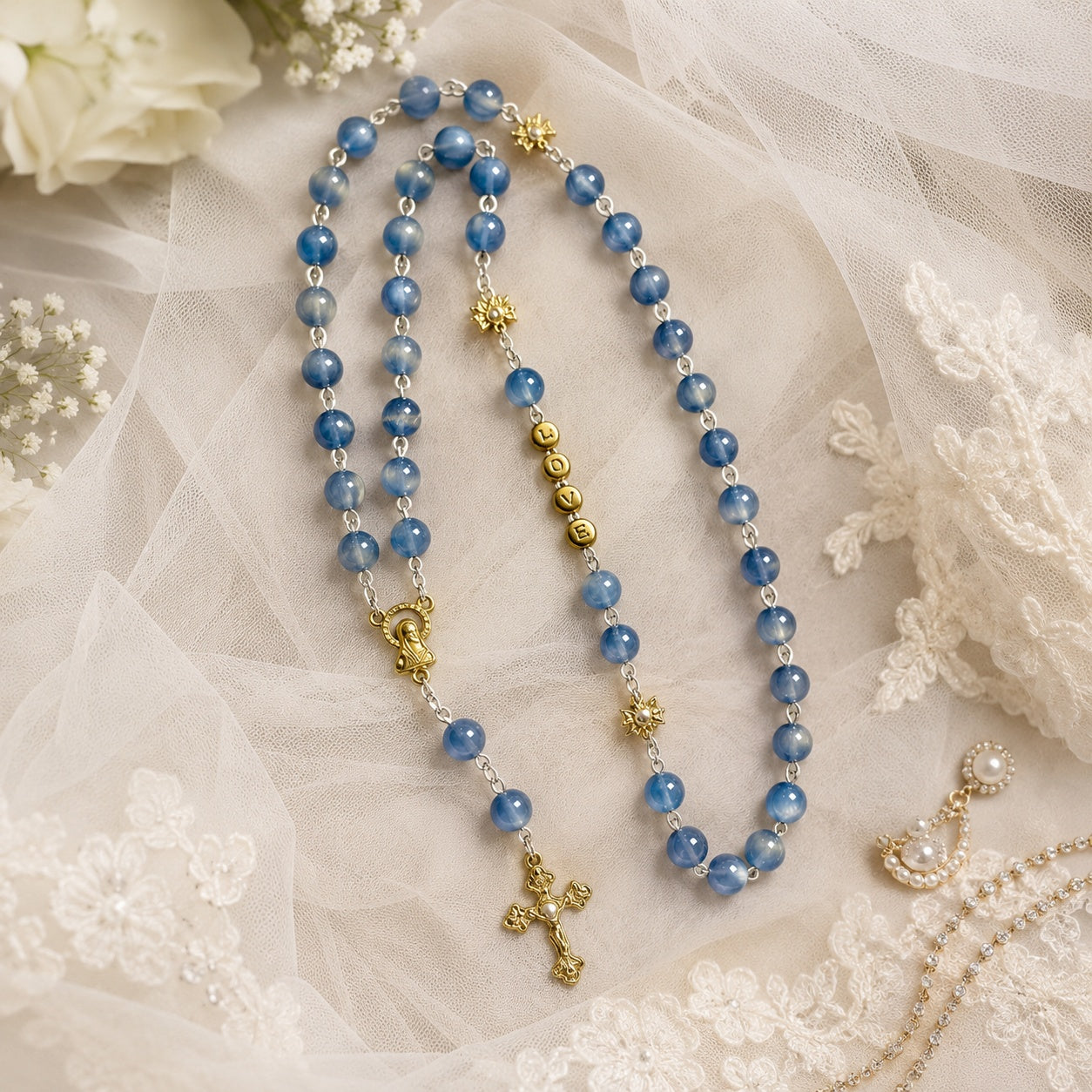 Blue Catholic bridal rosary displayed with wedding rings and ivory lace, designed as a meaningful Something Blue wedding keepsake