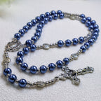 Traditional Catholic rosary with deep blue beads, silver crucifix, and Marian centerpiece arranged for daily prayer and devotion.