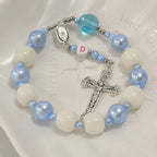 Blue and white Catholic car prayer beads with custom initial charm and silver crucifix, shown as a faith accessory for daily driving