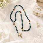 Romantic blue Catholic rosary for brides featuring gold-tone details, sacred heart accents, and a decorative crucifix, shown with wedding vow book, satin ribbon, and soft bridal flowers.