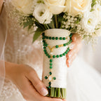 Bridal bouquet rosary with emerald green beads, gold-tone accents, pearl details, and a decorative Catholic cross pendant for wedding day prayer