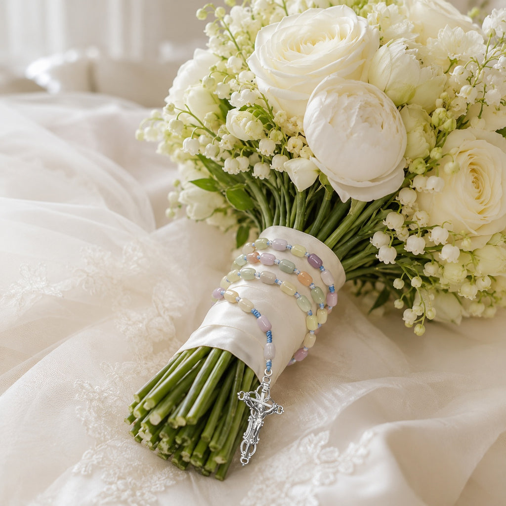 Bride holding a pastel Catholic rosary on a white wedding bouquet, designed as a meaningful marriage blessing keepsake
