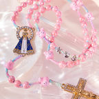 Close-up of a pink bunny Catholic rosary featuring rabbit charms, pastel woven cord, custom letters, and religious details.