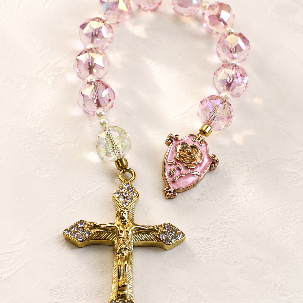 Pink crystal Catholic prayer beads with pearl accents, gold crucifix, and religious centerpiece designed as a meaningful faith gift.