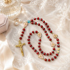 Bride holding a burgundy Catholic rosary with gold crucifix and rose medals, symbolizing faith, love, and marriage blessing