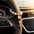 Catholic steering wheel rosary with pearl-style beads and gold crucifix, designed as a meaningful faith accessory for drivers