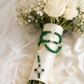 Emerald green Catholic wedding rosary for bride with gold details, pearl accents, and Marian cross pendant styled on a bridal bouquet