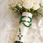 Emerald green Catholic wedding rosary for bride with gold details, pearl accents, and Marian cross pendant styled on a bridal bouquet