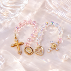 Handmade Catholic crystal charms with pink and clear beads, gold cross pendants, Marian medals, and heart charm details.