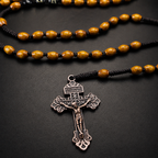 Close-up of antique bronze crucifix on a men's wooden Catholic rosary with rustic woven cord and brown prayer beads.