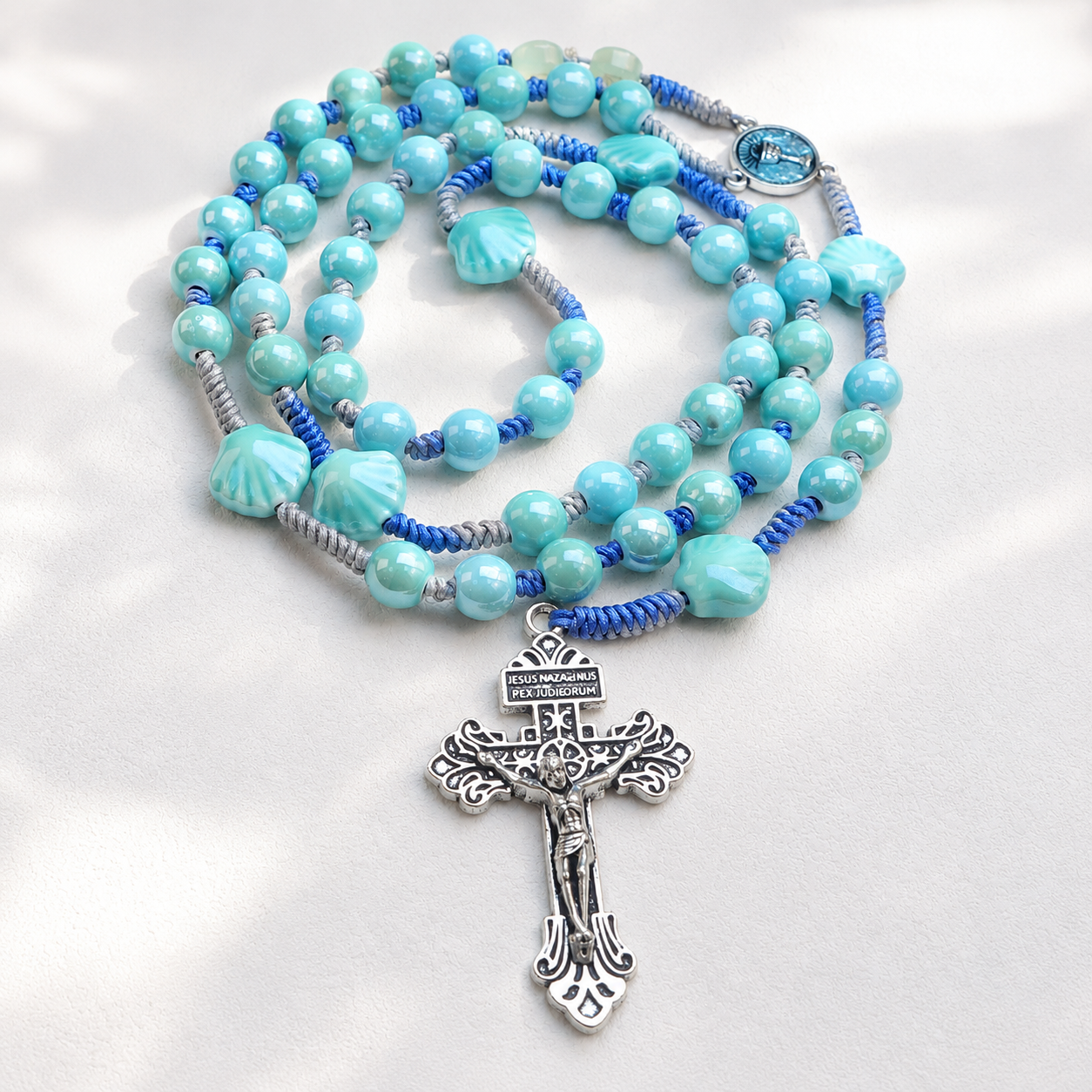 Turquoise seashell Catholic rosary with blue beads, silver crucifix, and handmade cord details for daily devotion and reflection.