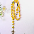 Cute ladybug Catholic rosary with bright yellow beads, handmade details, and religious charms arranged for Baptism and First Communion gifts.