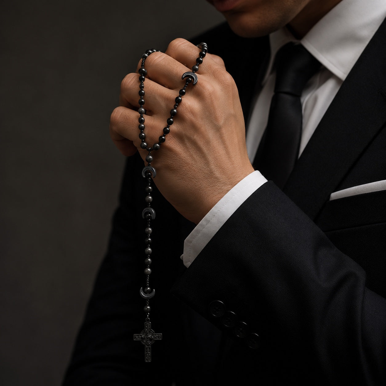 Black Catholic rosary for men with dark prayer beads and black crucifix, displayed on a soft ivory fabric background for a masculine religious keepsake.