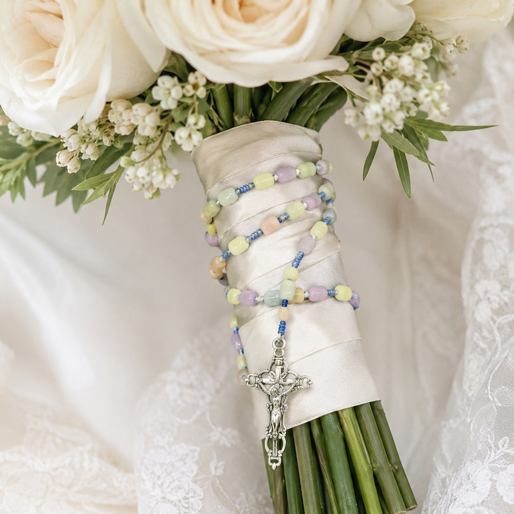 Soft pastel bridal bouquet rosary with silver crucifix, handmade-style prayer beads, and gentle wedding floral styling