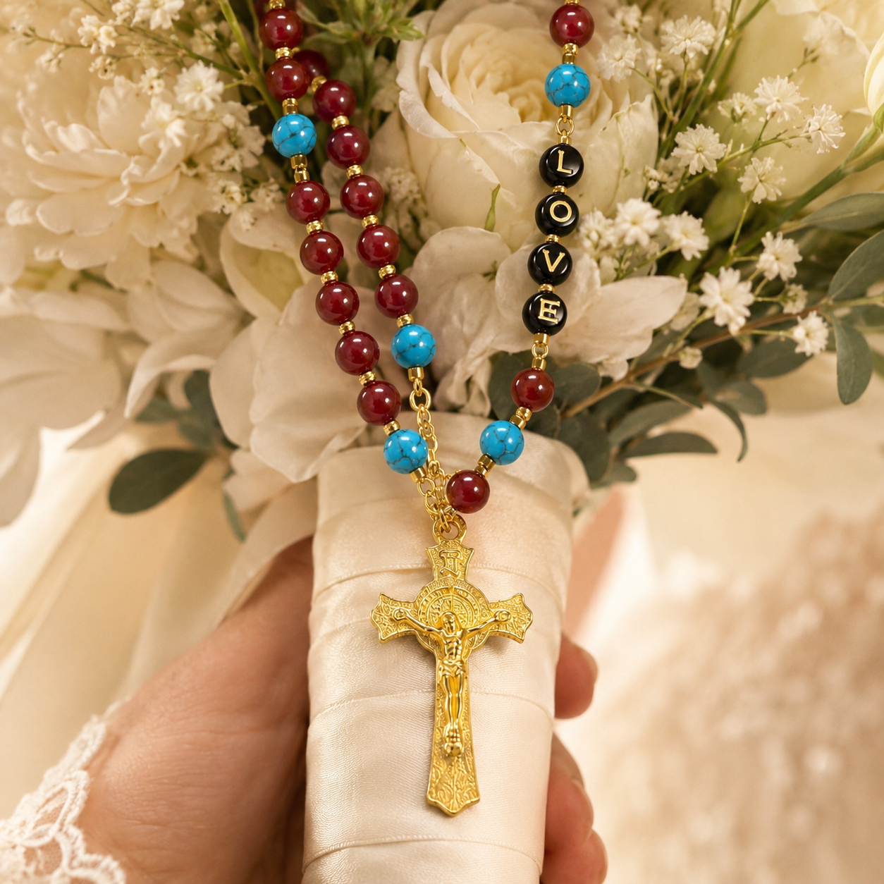 Red Catholic wedding rosary displayed on soft bridal lace with gold crucifix, LOVE beads, and elegant wedding accessories