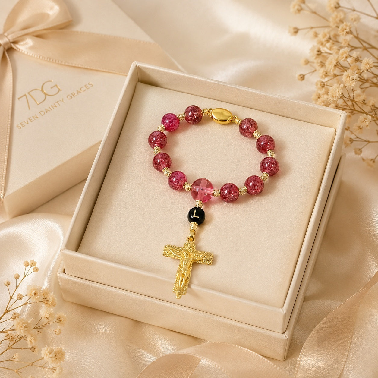 Red Catholic car prayer beads displayed on a black steering wheel, featuring crystal-style beads, gold crucifix, and custom initial charm