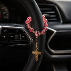 Elegant red Catholic car rosary with textured beads, gold crucifix, and personalized letter bead designed as a faith accessory for drivers