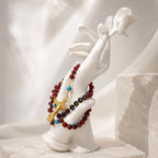 Red Catholic prayer beads with gold spacers, crucifix, and LOVE beads arranged on dark wood with cream satin fabric