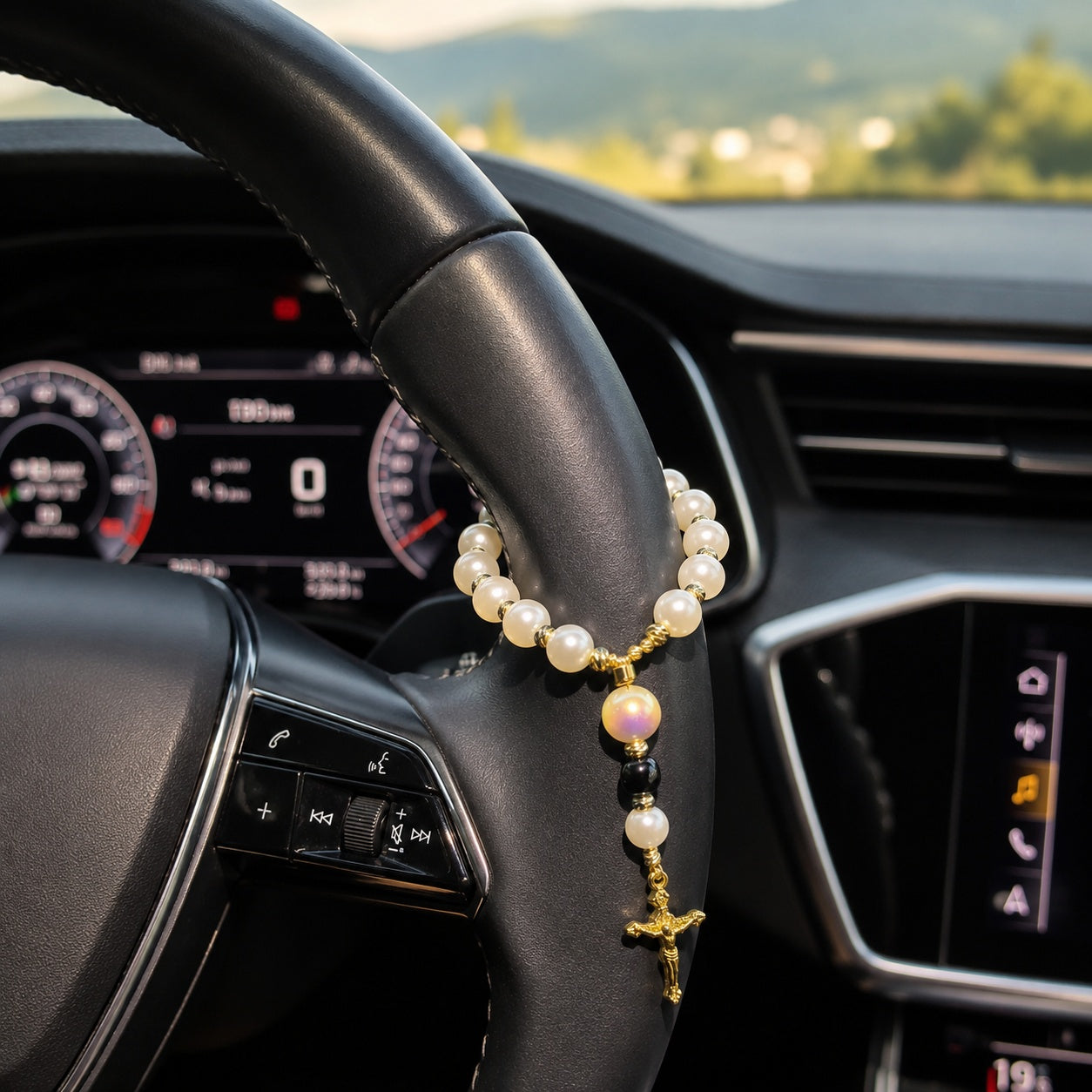 Pearl car prayer beads displayed in a white dish beside a candle and Christian decor, featuring a gold crucifix and initial bead