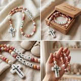 A detailed close-up of a handmade personalized silicone rosary with colorful beads, a white 'Jesus' script cross, letter beads for names STEVIE and MARI, and surrounding delicate flowers.