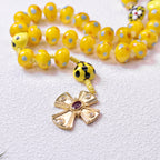 Close-up of a yellow Catholic rosary featuring a gold-tone crucifix, ladybug bead accents, and colorful prayer beads with a cute faith-inspired design.